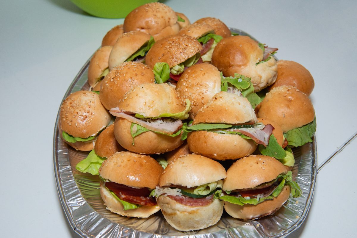 A dsiposable tray with mini sandwiches in bread rolls..
